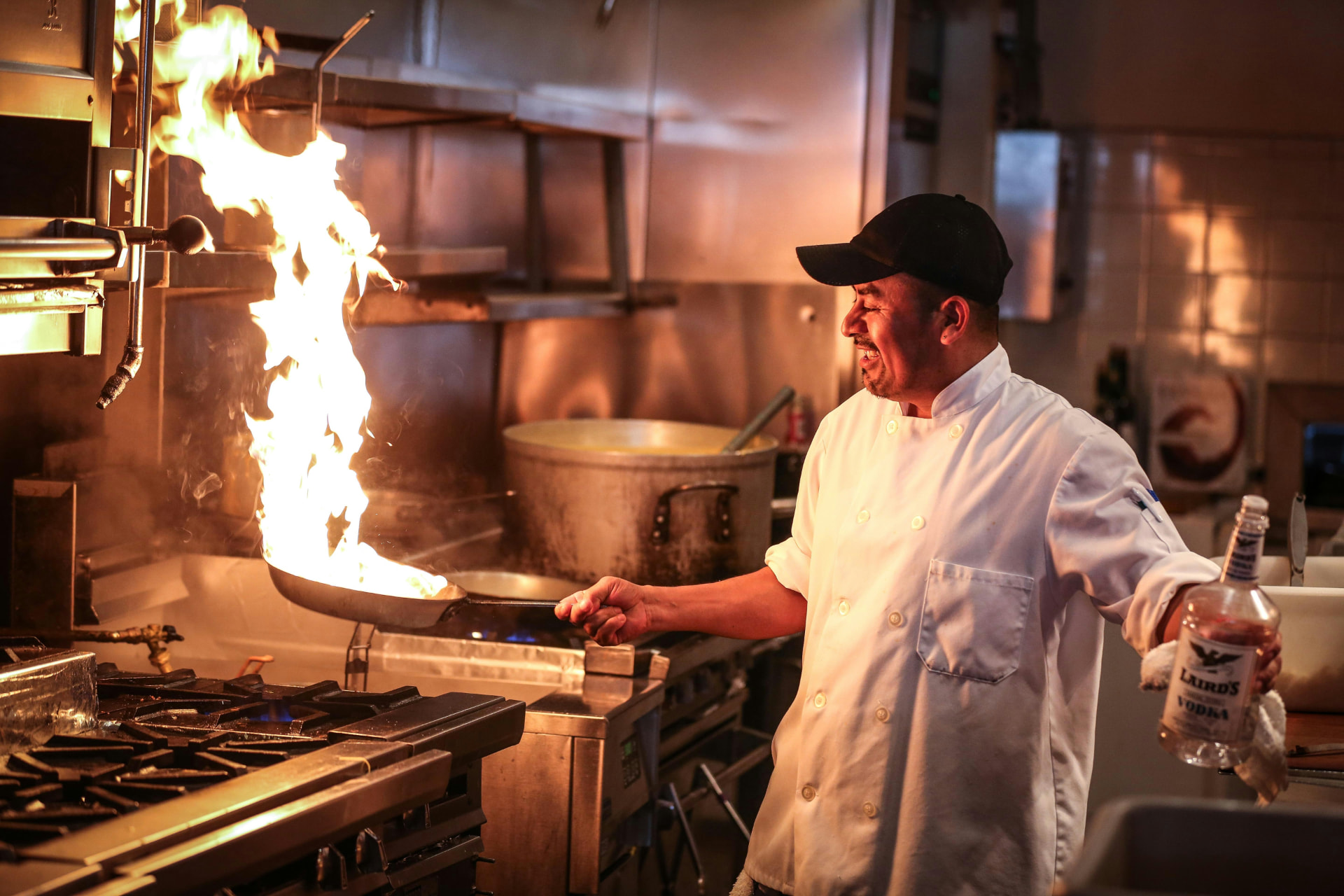 A chef flambéing a pan over the stove