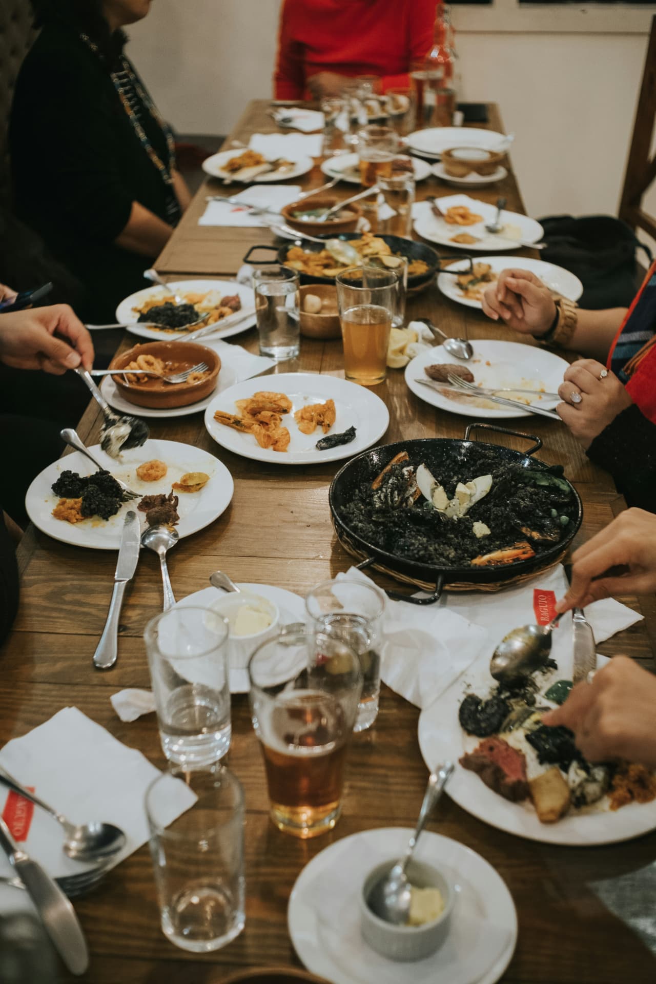 Friends sharing paella and tapas along a long wooden table