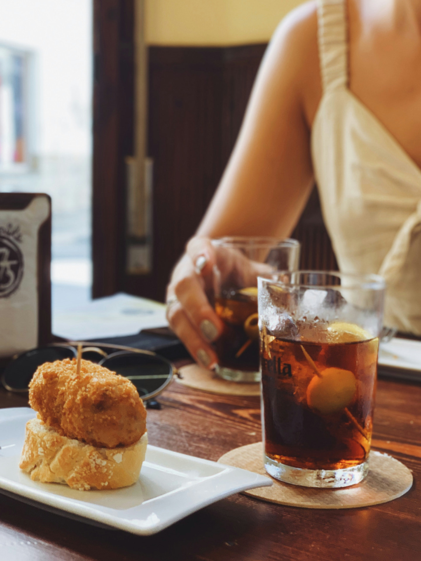 A croqueta pintxo beside a glass of vermouth