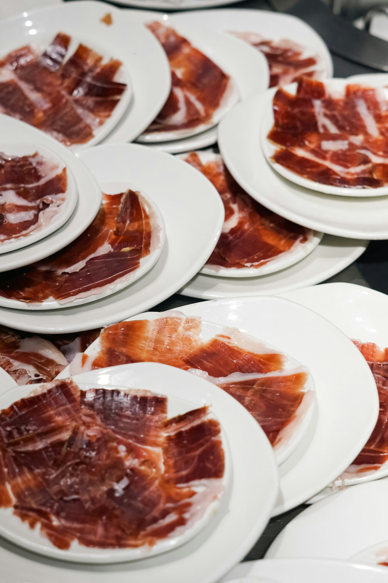 Thin slices of jamón ibérico arranged across white plates