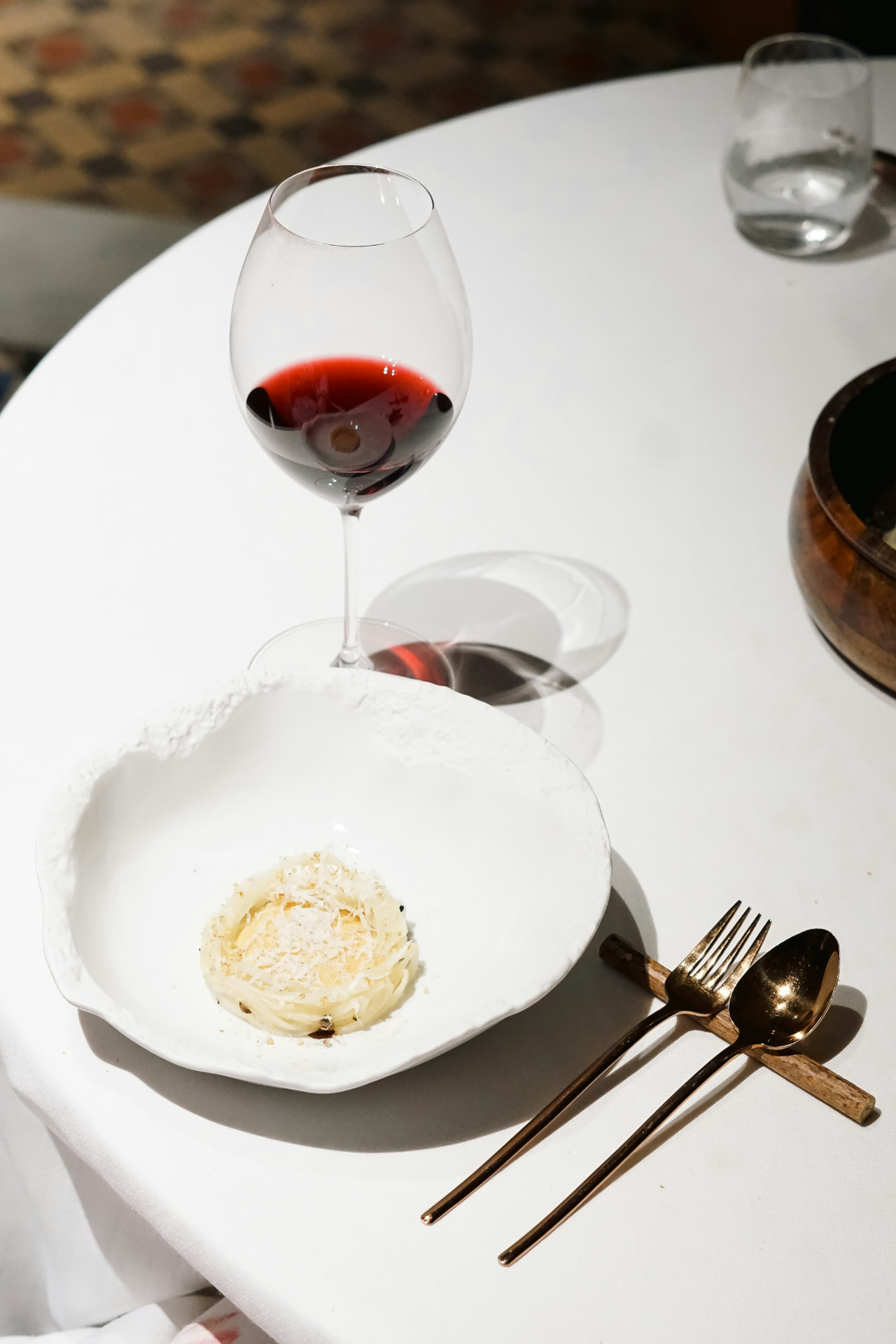 A composed seasonal plate beside a glass of Rioja