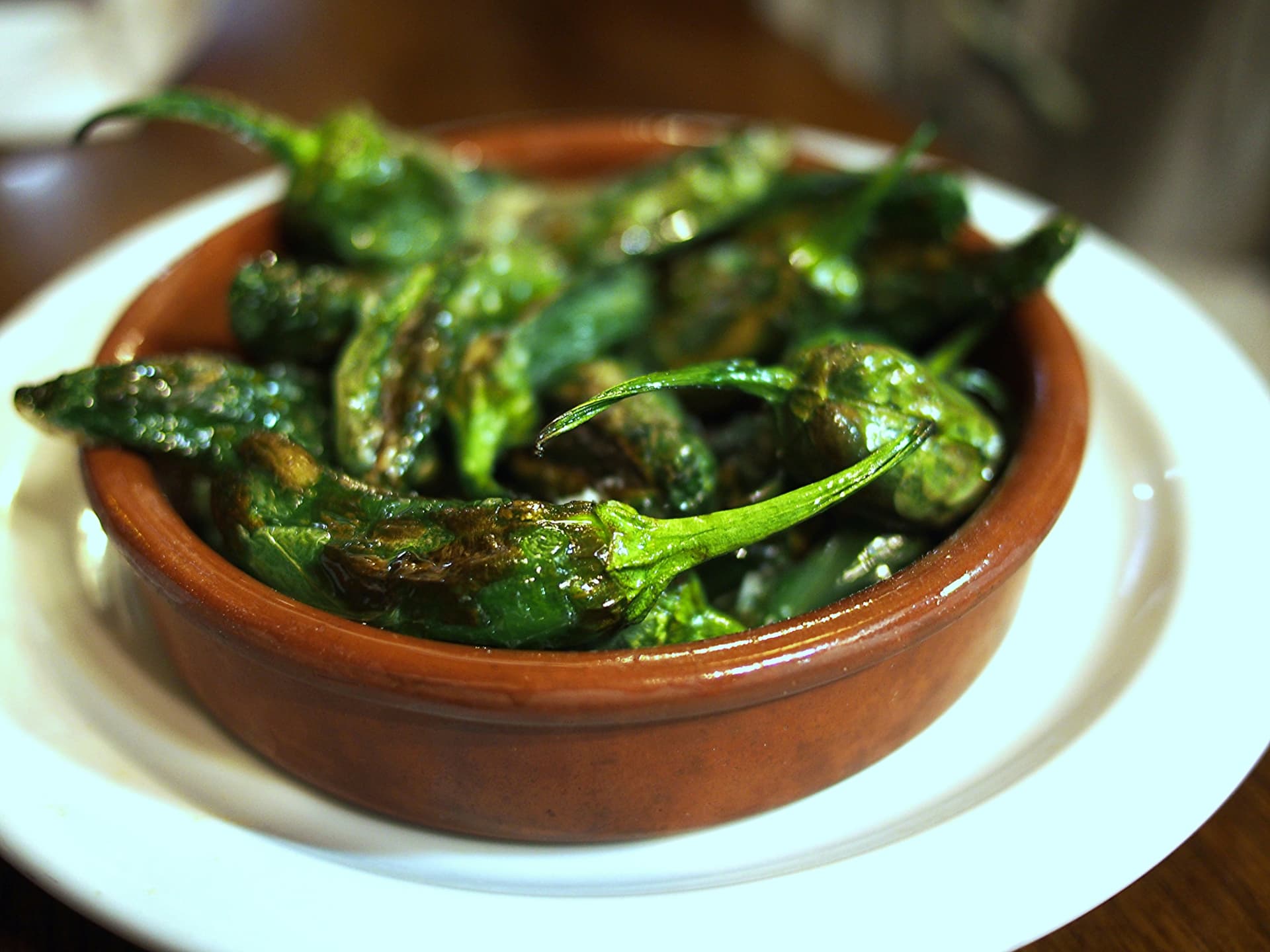 Blistered pimientos de Padrón in a terracotta dish